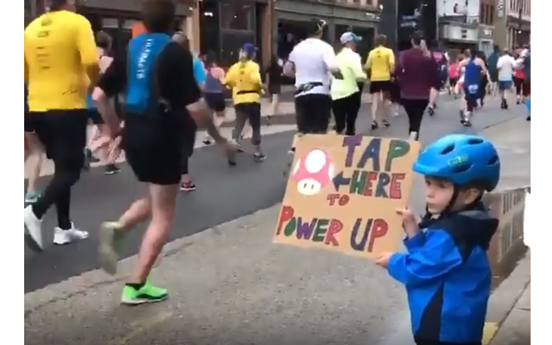 小萌娃自製加油板為馬拉松選手打氣，貼心的標語被「選手搶著摸」參賽者稱：加油板有魔力